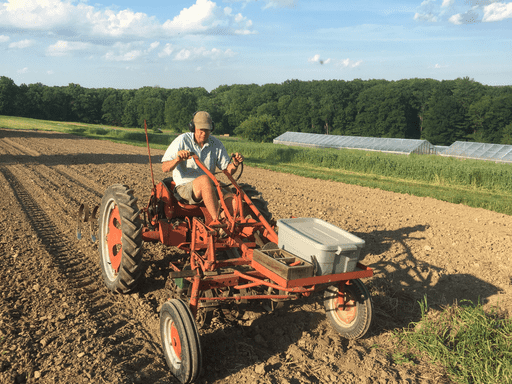 A picture of Raymond seeding with Allis Chalmers G tractor and planet Jr. seeders